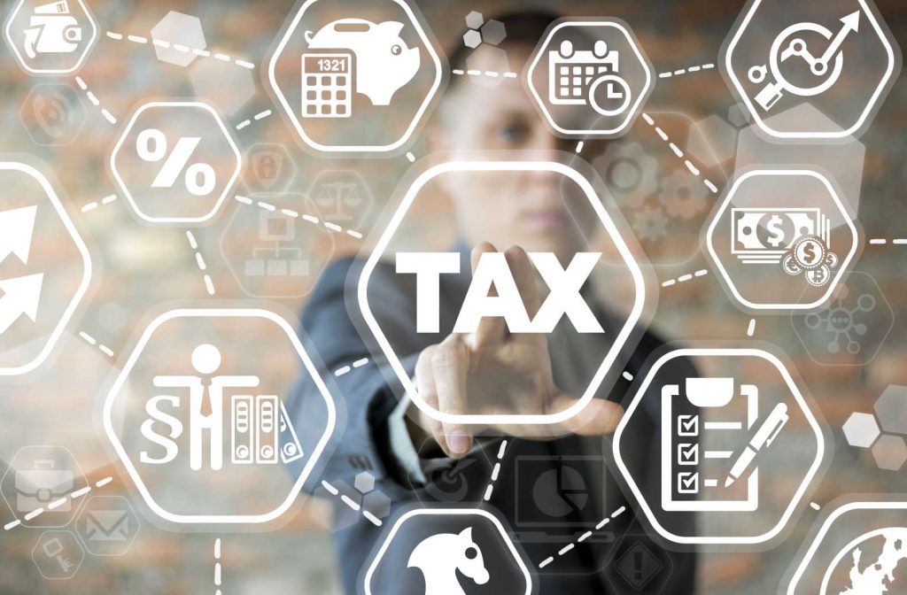 A man reaching out to touch the word "tax" in a web displaying different tax strategies.